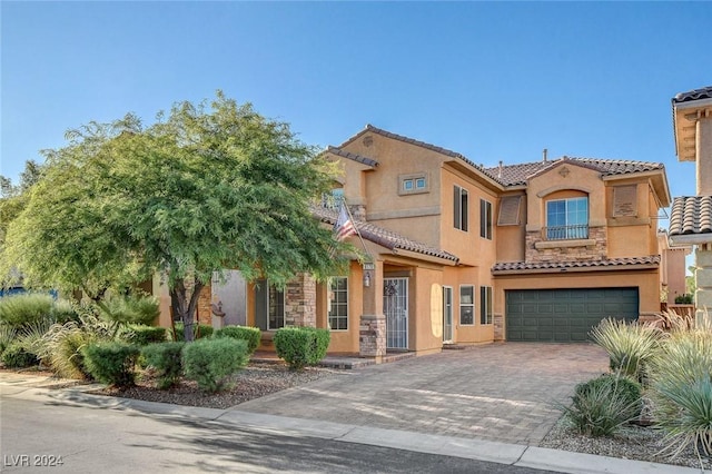 mediterranean / spanish home with a tile roof, decorative driveway, a garage, and stucco siding