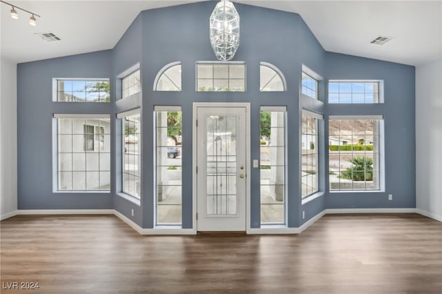 doorway featuring hardwood / wood-style floors, lofted ceiling, and an inviting chandelier