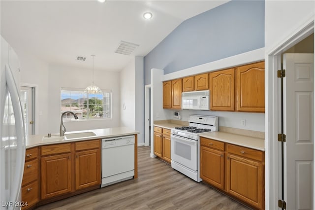 kitchen with white appliances, sink, light hardwood / wood-style flooring, hanging light fixtures, and lofted ceiling