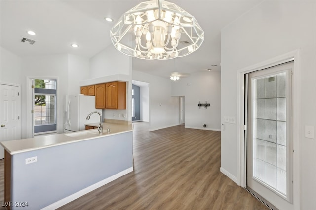 kitchen with sink, an inviting chandelier, light hardwood / wood-style flooring, kitchen peninsula, and white fridge