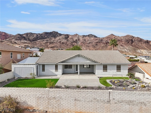 rear view of house with a lawn, a mountain view, and a patio area