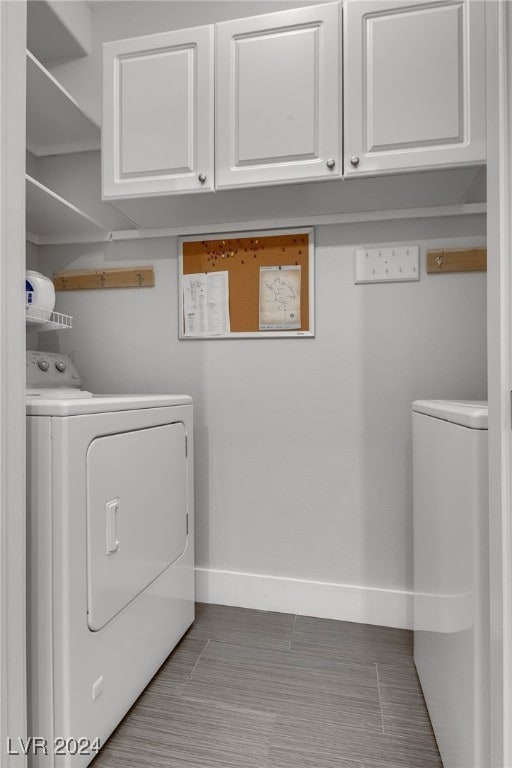 clothes washing area with cabinet space, independent washer and dryer, and baseboards