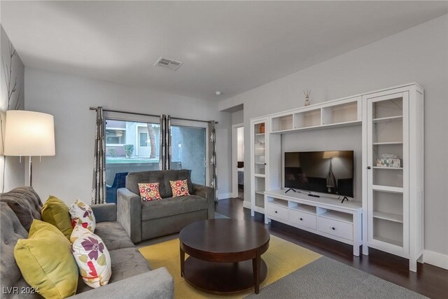 living room featuring dark wood-style floors, visible vents, and baseboards