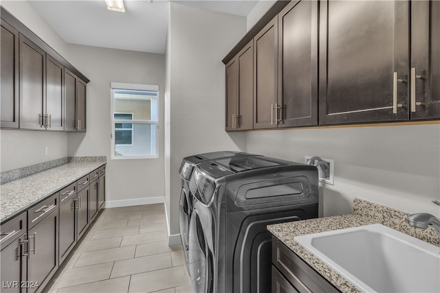 laundry room featuring washing machine and dryer, sink, light tile patterned floors, and cabinets