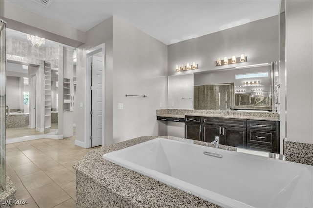 bathroom with tile patterned flooring, vanity, and a relaxing tiled tub