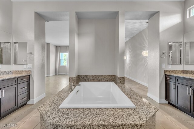 bathroom with vanity, a relaxing tiled tub, and a wealth of natural light