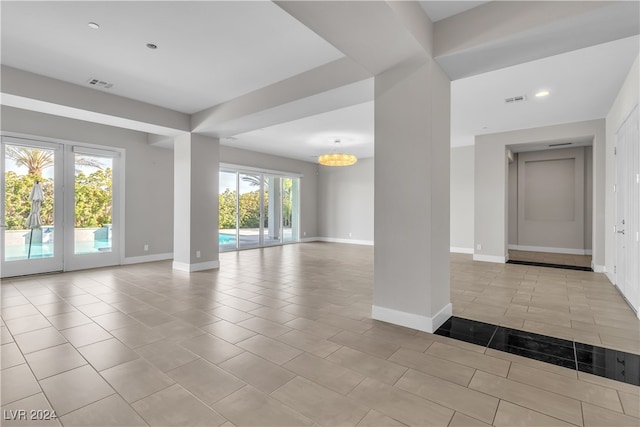 tiled empty room with an inviting chandelier