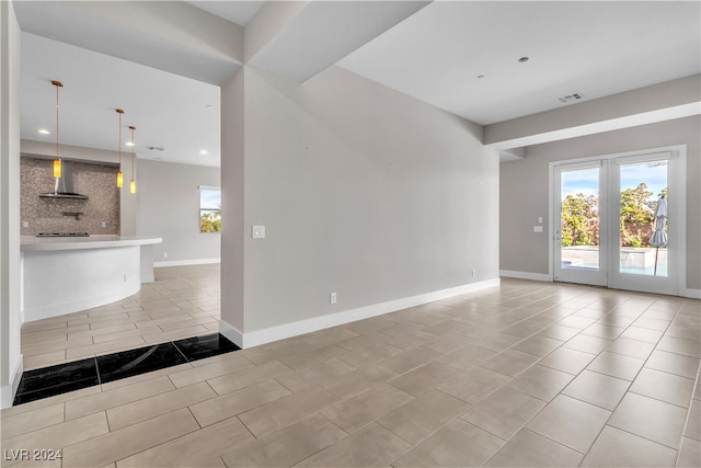 unfurnished living room featuring light tile patterned flooring and french doors