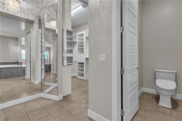 bathroom with a washtub, tile patterned flooring, and toilet