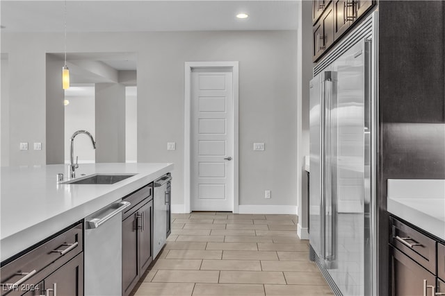 kitchen featuring pendant lighting, dark brown cabinets, stainless steel dishwasher, and sink