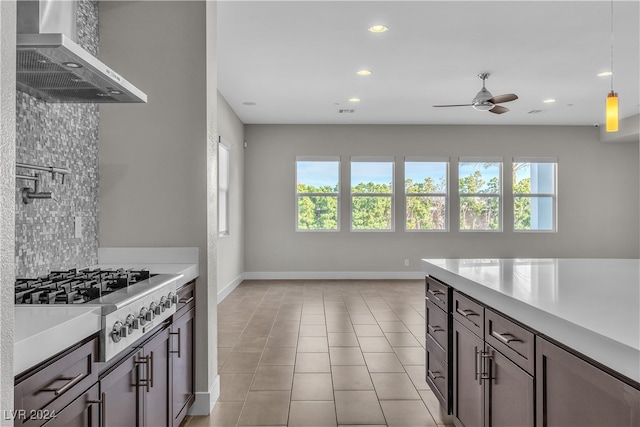 kitchen featuring dark brown cabinets, a healthy amount of sunlight, and wall chimney range hood