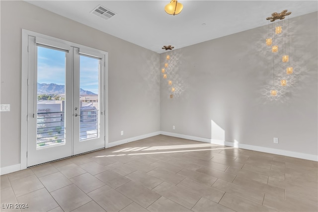 unfurnished room featuring a mountain view, french doors, and light tile patterned floors