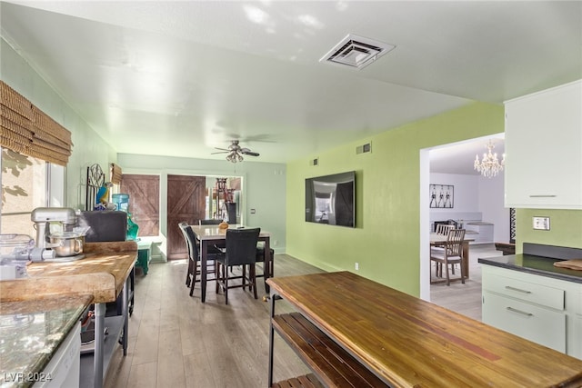 dining space featuring ceiling fan with notable chandelier and light hardwood / wood-style flooring