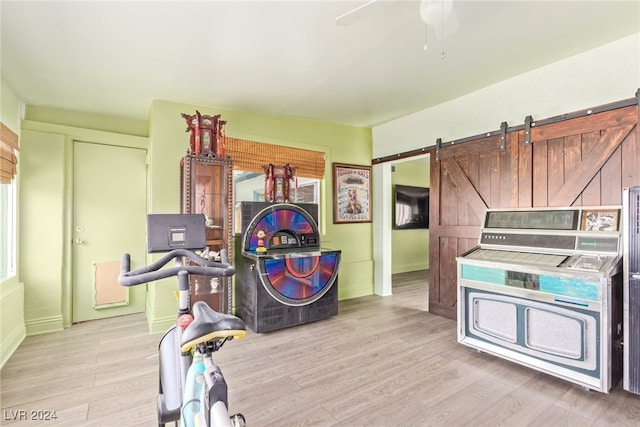 interior space with ceiling fan, light hardwood / wood-style floors, a barn door, and washer / clothes dryer