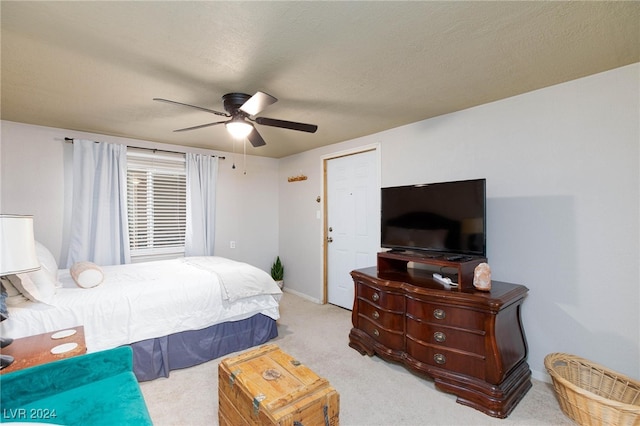 bedroom with ceiling fan, light colored carpet, and a textured ceiling