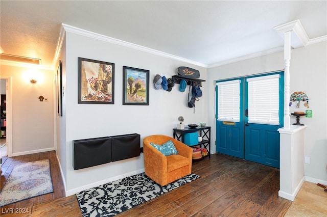 foyer featuring crown molding, dark wood-type flooring, and ornate columns