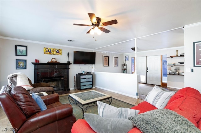 living room featuring a tile fireplace, tile patterned flooring, ceiling fan, and crown molding