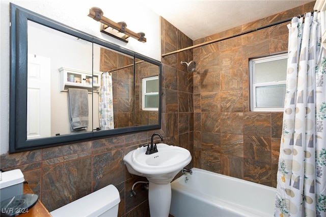 bathroom with toilet, shower / bath combo with shower curtain, and tile walls