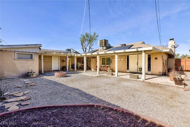 rear view of house featuring central air condition unit, a patio area, a fire pit, and solar panels