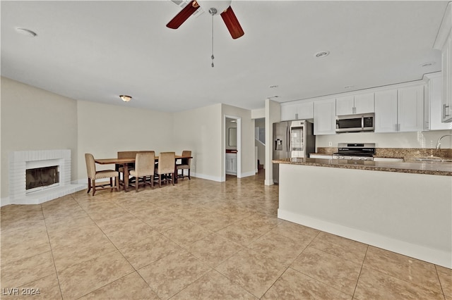 kitchen featuring ceiling fan, sink, stainless steel appliances, dark stone countertops, and white cabinets