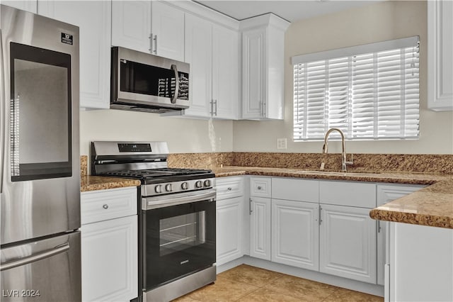 kitchen with light tile patterned floors, white cabinetry, sink, and appliances with stainless steel finishes