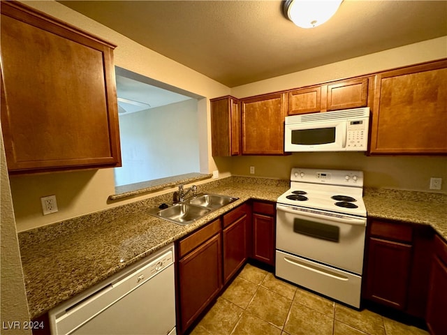 kitchen with light tile patterned flooring, white appliances, and sink