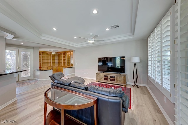 living room featuring ceiling fan, a raised ceiling, and light hardwood / wood-style flooring