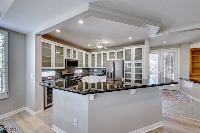 kitchen with white cabinets, a kitchen bar, backsplash, and appliances with stainless steel finishes