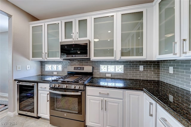 kitchen featuring white cabinets, appliances with stainless steel finishes, light tile patterned floors, and beverage cooler