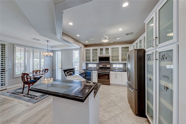 kitchen featuring kitchen peninsula, appliances with stainless steel finishes, tasteful backsplash, sink, and white cabinetry