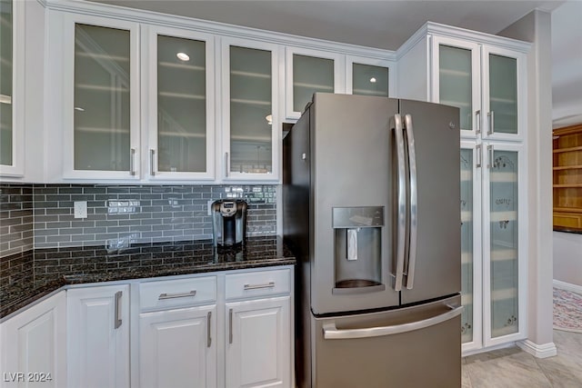 kitchen featuring tasteful backsplash, dark stone counters, stainless steel fridge with ice dispenser, white cabinetry, and light tile patterned flooring