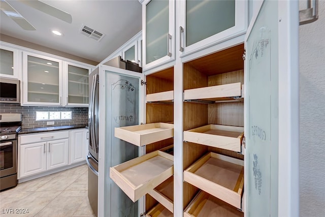 interior space featuring white cabinetry, ceiling fan, stainless steel appliances, tasteful backsplash, and light tile patterned floors