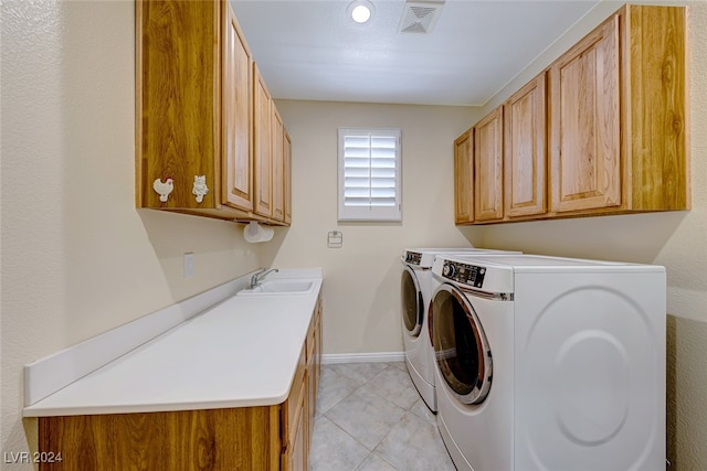 laundry room featuring washing machine and dryer, sink, light tile patterned floors, and cabinets