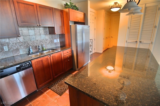 kitchen featuring pendant lighting, sink, decorative backsplash, dark stone countertops, and appliances with stainless steel finishes