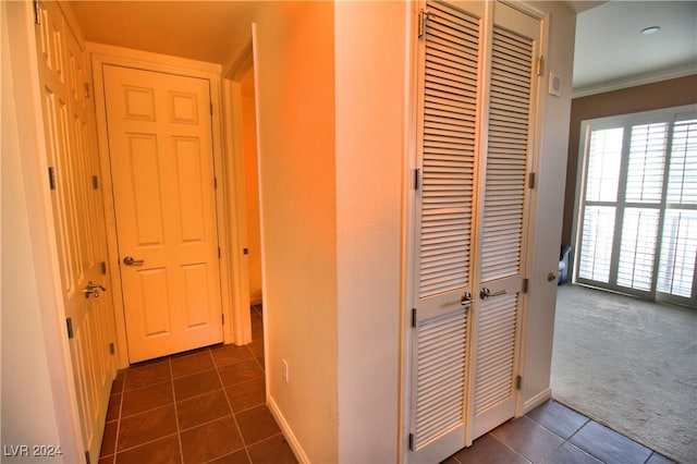 hall with dark tile patterned floors and crown molding