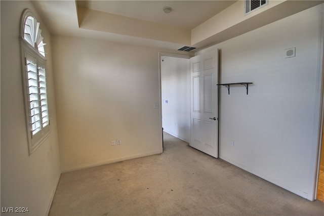 carpeted spare room with a raised ceiling