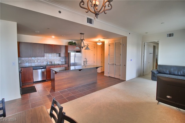 kitchen featuring tasteful backsplash, stainless steel appliances, decorative light fixtures, dark tile patterned flooring, and a kitchen island