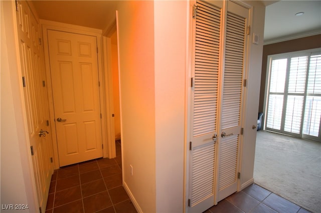 hall featuring dark tile patterned floors and ornamental molding