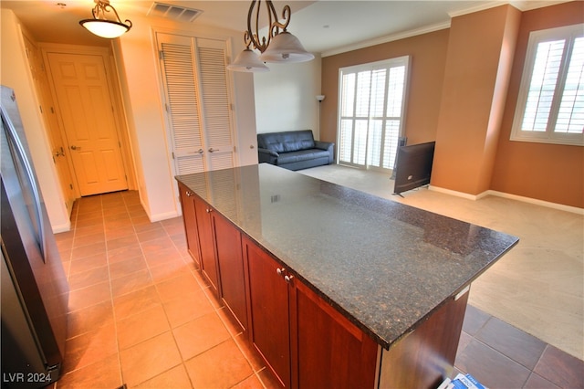 kitchen featuring a kitchen island, hanging light fixtures, ornamental molding, and dark stone countertops