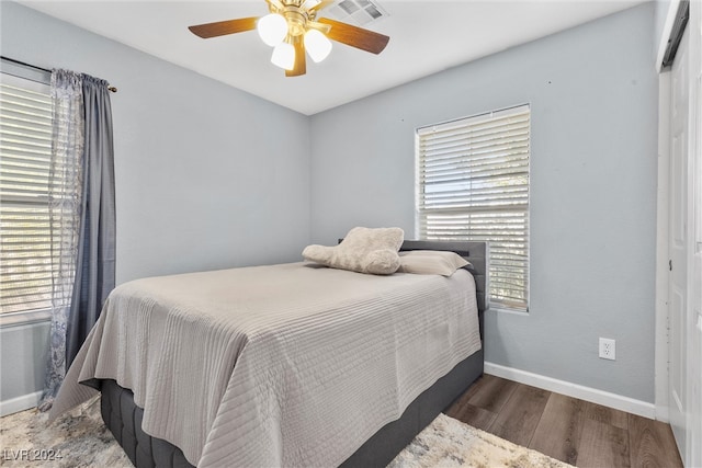 bedroom featuring ceiling fan, dark wood-type flooring, and multiple windows