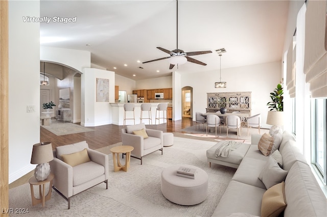 living room featuring ceiling fan, light hardwood / wood-style floors, and vaulted ceiling