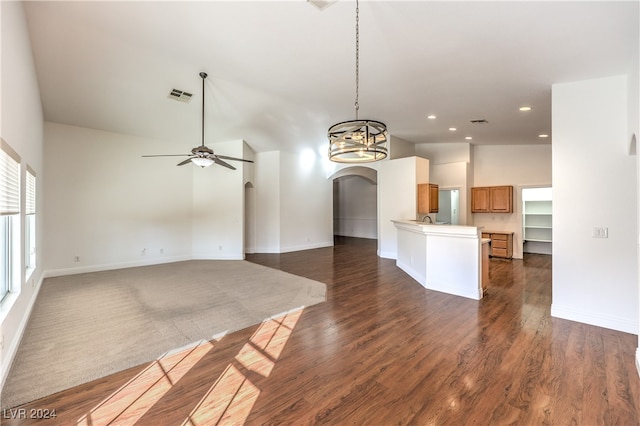 interior space featuring ceiling fan with notable chandelier, sink, kitchen peninsula, and dark wood-type flooring