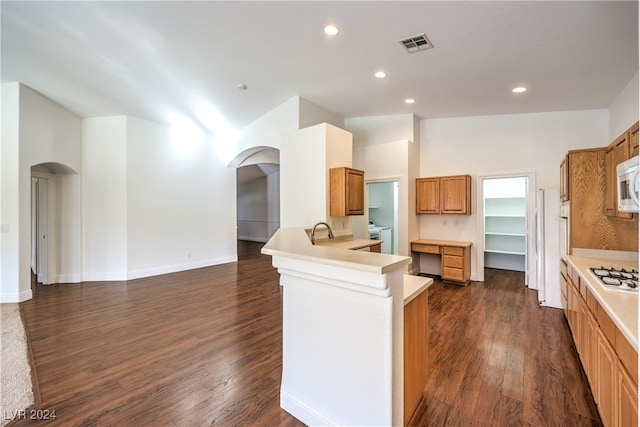 kitchen with sink, high vaulted ceiling, dark hardwood / wood-style floors, kitchen peninsula, and white appliances