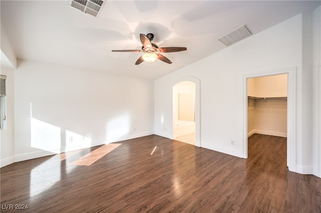 unfurnished bedroom featuring a closet, dark hardwood / wood-style floors, a spacious closet, and ceiling fan