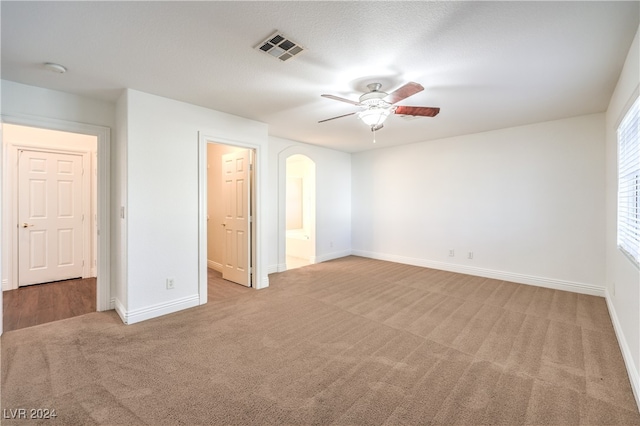 unfurnished bedroom with ceiling fan, ensuite bathroom, and light carpet