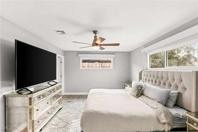 bedroom featuring multiple windows, wood-type flooring, and ceiling fan