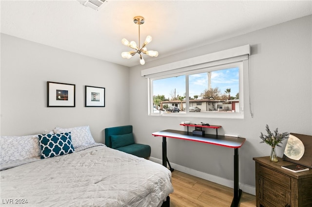 bedroom with a notable chandelier and light wood-type flooring