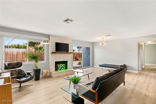 living room featuring light hardwood / wood-style flooring, a textured ceiling, a fireplace, and a chandelier