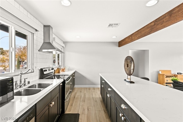 kitchen with wall chimney exhaust hood, sink, stainless steel appliances, beam ceiling, and backsplash