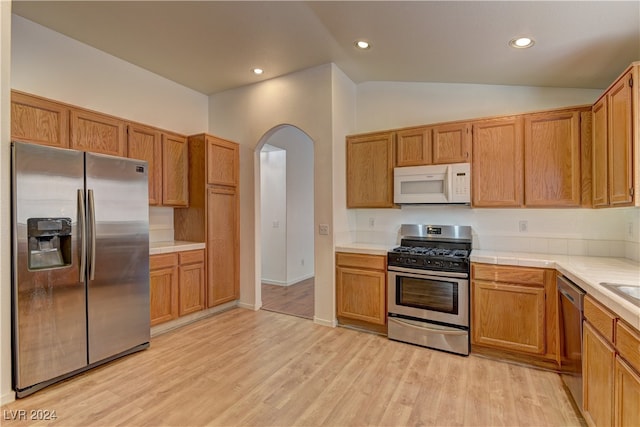 kitchen featuring lofted ceiling, appliances with stainless steel finishes, and light hardwood / wood-style flooring